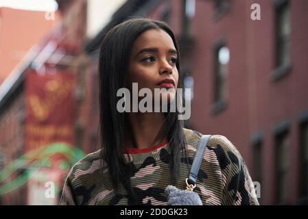 Giovane donna afroamericana in camouflage vestito in piedi sulla strada A New York e guardando via Foto Stock