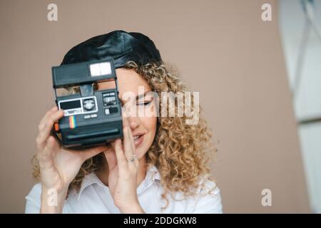 Fotografo femminile con fotocamera retrò istantanea per scattare foto sfondo marrone in studio Foto Stock