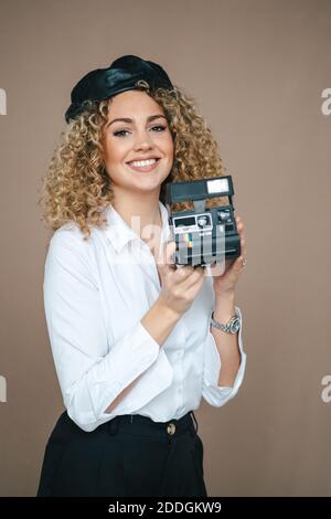 Fotografo femminile con fotocamera retrò istantanea per scattare foto sfondo marrone in studio Foto Stock