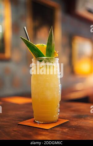 Bicchiere di cocktail tropicale con ananas e foglie sul banco in bar Foto Stock