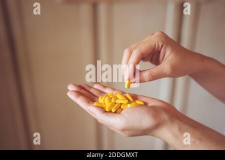 Dall'alto del palmo di raccolto di persona anonima che dimostra mucchio di pillole di vitamina gialla per il concetto sano di stile di vita Foto Stock