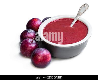 Chutney fatto in casa da prugne in ciotola di argilla isolato su bianco Foto Stock