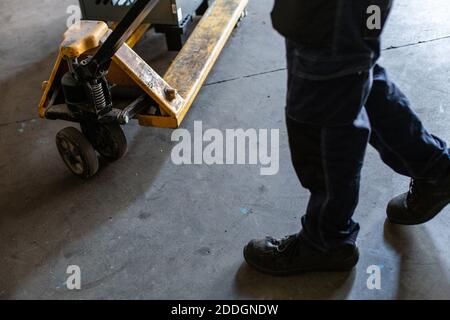 Vista laterale del carrello di traino anonimo del coltivatore con pesante attrezzature metalliche durante il lavoro in un'officina di assistenza professionale Foto Stock
