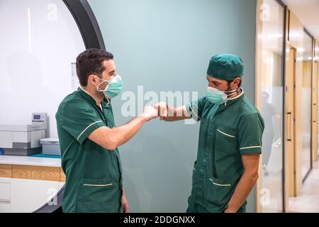 Vista laterale i medici maschi che fanno il pugno gesto mentre si è in piedi nel corridoio dell'ospedale Foto Stock
