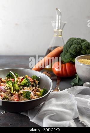 Ciotola con salutare insalata di couscous di bulgur fatta in casa con verdure varie e noci servite a tavola con ingredienti Foto Stock