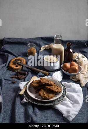 Un'ampia gamma di appetitosi biscotti fatti in casa con farinata d'avena posti sul tavolo con ingredienti assortiti Foto Stock
