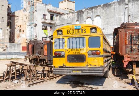 Un tipico autobus scolastico giallo vintage Blue Bird parcheggiato in un cantiere ferroviario nel centro di Old Havana, capitale di Cuba Foto Stock