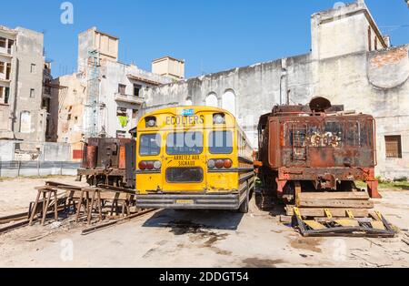 Un tipico autobus scolastico giallo vintage Blue Bird parcheggiato in un cantiere ferroviario nel centro di Old Havana, capitale di Cuba Foto Stock