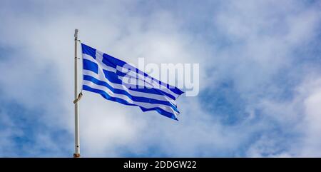 Bandiera greca che oscilla sul palo contro sfondo blu cielo nuvoloso, copia spazio. Simbolo nazionale della Grecia Foto Stock