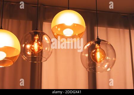 Diverse lampade in stile retrò all'interno di una spirale elettrica in luce calda in vetro doppio sospeso sopra il tavolo Foto Stock