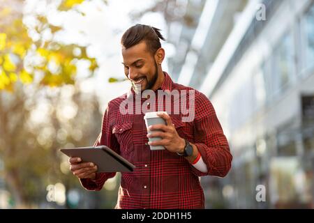 Giovane uomo che usa il tablet digitale all'aperto in ambiente urbano Foto Stock