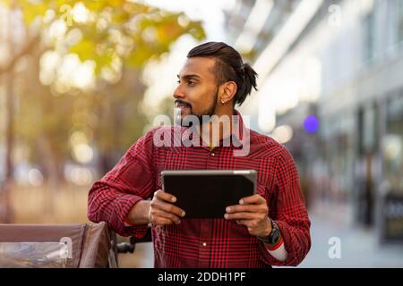 Giovane uomo che usa il tablet digitale all'aperto in ambiente urbano Foto Stock