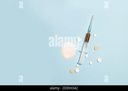 Giornata internazionale contro l'abuso di droghe. Preparazioni mediche polvere o capsule di diversi colori, siringa con iniezione di eroina farmaco su sfondo blu. Foto verticale. Concetto di stile di vita sano. Posiziona per il testo Foto Stock