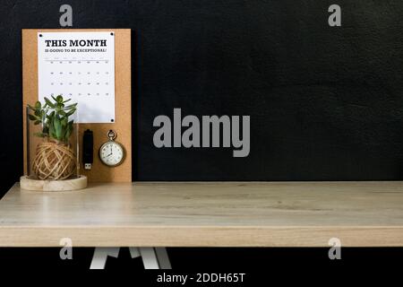Questo ufficio domestico ha una bacheca di avviso di sughero con un calendario, un orologio da tasca vintage e un'unità flash USB fissata ad esso. La scrivania è organizzata e ordinata. Foto Stock