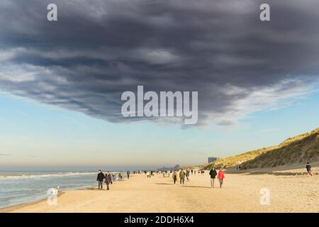 Oostduinkerke, Belgio - 6 novembre 2020: Folla sulla spiaggia che cammina sotto una strana nuvola minacciosa Foto Stock