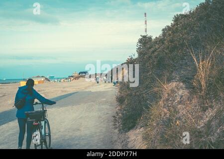 Una donna che cavalcano una bicicletta sulla spiaggia di Borkum, in Germania Foto Stock