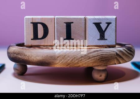 Testo fai-da-te su blocchi cubici di legno. Le lettere DIY scritte sui cubi in lettere nere. Testo fai-da-te per il tuo desing. Foto Stock