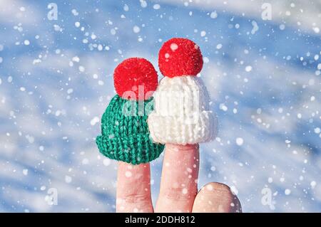 Accoppia le dita in cappelli di lana lavorato a maglia contro lo sfondo invernale blu fiocco di neve. Felice famiglia festeggia il concetto per Natale o Capodanno Foto Stock