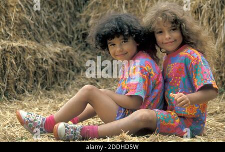 due piccole sorelle che si siedono sulla balla di fieno Foto Stock