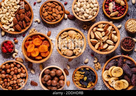 Varie noci e frutta secca in ciotole di legno, vista dall'alto. Foto Stock