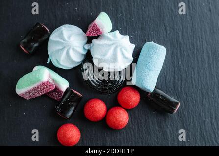 Dolci caramelle nere alla liquirizia, colorata marmellata di frutta in zucchero e marshmallow sparsi su una parte superiore nera di stale. Foto Stock