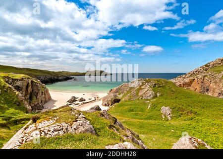 ACHMELVICH BAY LOCHINVER SUTHERLAND SCOZIA FIORI SELVATICI SULLE SCOGLIERE UNA SPIAGGIA DI SABBIA BIANCA E UN BLU CHIARO E TURCHESE MARE Foto Stock