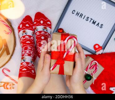Cartellone con l'iscrizione Natale, piedi in calze rosse, e regali Foto Stock