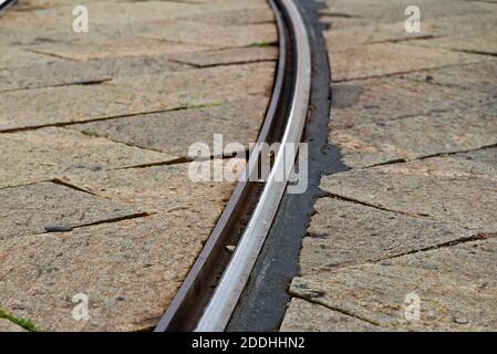 Binari ferroviari in strada asfaltata, primo piano. . Foto Stock