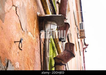 immagine di una lanterna e di un tubo di raccolta arrugginito sul muro di una casa Foto Stock