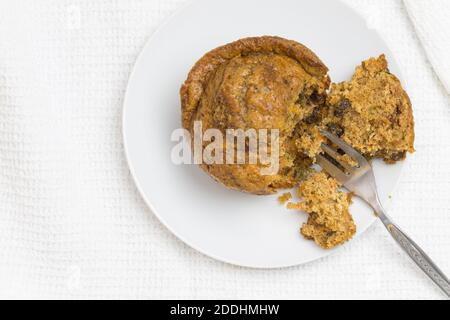 Muffin con forchetta per torta, foto dall'alto con messa a fuoco selettiva e spazio di copia su bianco - muffin alla carota, alla mela, alla cannella e all'uvetta Foto Stock