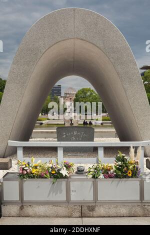 Vista ravvicinata del Cenotafh Memoriale alle vittime della seconda guerra mondiale con la cupola della bomba atomica e la fiamma della pace sullo sfondo, Hiroshima, Giappone Foto Stock