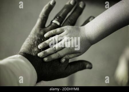 La mano di mia figlia sopra la mia. Riprese con luce UV. Foto Stock