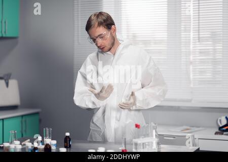 Un giovane farmacista maschile al lavoro in una sala da laboratorio luminosa e spaziosa. Foto Stock