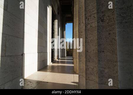 Una vista in primo piano di un lungo corridoio con colonne e. luce solare diretta su di loro Foto Stock