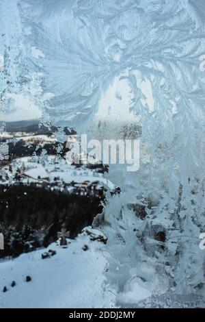 Sfondo invernale, Window.Ice frosty motivi su inverno glass.Frosty modello fiocco di neve su una finestra invernale, al di fuori della foresta e paesaggio di montagna.Chris Foto Stock