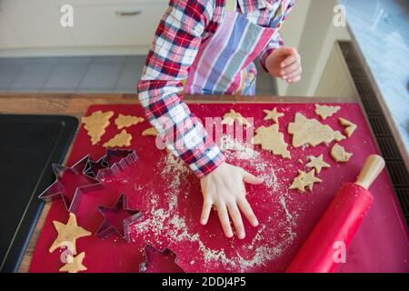 Primo piano di mani di peperoncini che fanno natale zenzero biscotti di forme diverse nella cucina moderna Foto Stock