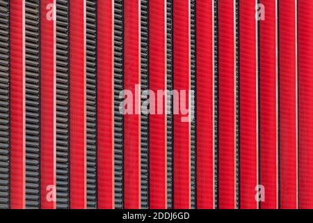 Immagine di sfondo: Pannelli decorativi posizionati verticalmente in rosso con barre nere tra loro. Foto Stock