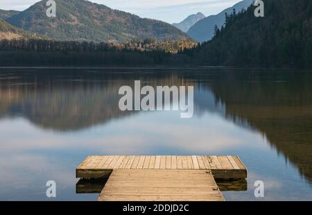 Piccolo molo in legno presso il lago Deer, British Columbia isolato sullo sfondo delle montagne. Messa a fuoco selettiva, foto di viaggio, nessuno. Foto Stock