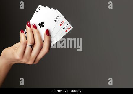 Quattro assi che giocano le carte in mano della donna. Giocatore con combinazione di quads di poker. Eleganti mani femminili con manicure rossa sui chiodi. Foto Stock