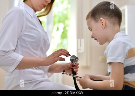 Il medico e il bambino vengono introdotti all'apparecchiatura medica con uno stetoscopio. Abbiamo divertimento e ci piace socializzare insieme. Foto Stock