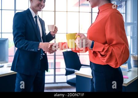 I partner commerciali scuotono le mani con una tazza da caffè. Concetto di cooperazione commerciale. Foto Stock