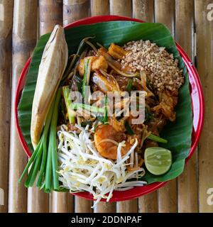 Vista dall'alto del cibo thailandese tradizionale, pad thai, servire su piatto su tavolo di bambù. Foto Stock