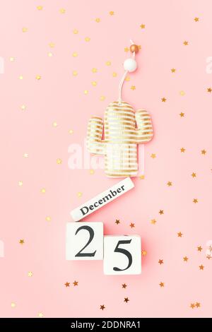 Calendario in legno Dicembre 25, cactus di natale in oro tessile e stelle confetti su sfondo rosa. Concetto alternativo di albero di natale di Merry. Vista dall'alto F Foto Stock