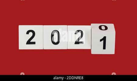 cubetti di legno bianco con numeri neri 2021 su sfondo rosso. felice xmas. numeri simboleggiano l'arrivo del nuovo anno Foto Stock