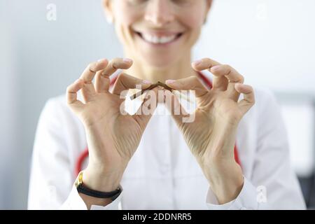 Medico che tiene la sigaretta in mano e la rompe primo piano della clinica Foto Stock