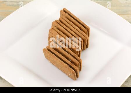 Pila di biscotti al panino riempiti di crema di cioccolato su uno spuntino bianco piastra Foto Stock