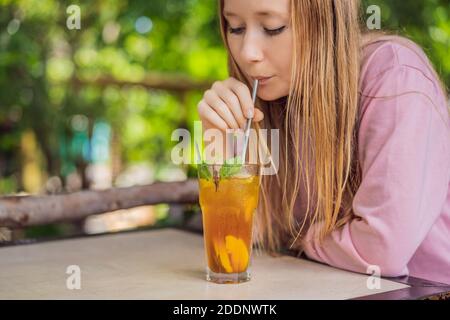 Donna ecocompatibile che utilizza paglia in acciaio inossidabile riutilizzabile per bere tè alla frutta Foto Stock