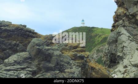 Il vecchio faro di Pencarrow si affaccia sullo stretto di Cook a Wellington NZ, preso dalla strada costiera ghiaiosa Foto Stock
