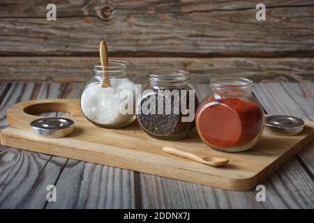 Varie erbe e spezie colorate in contenitore di vetro su legno sfondo Foto Stock
