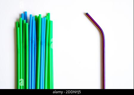 una pila di cannucce monouso in plastica e una riutilizzabile cannuccia da bere in acciaio inox su fondo bianco Foto Stock